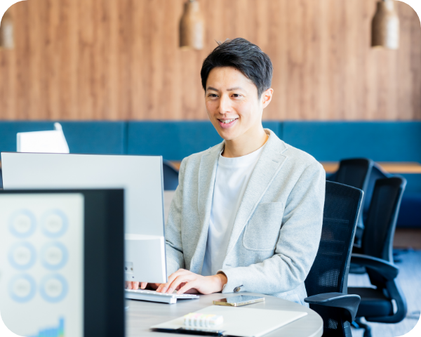 画像：男性がPCを見ながら笑顔で働いている